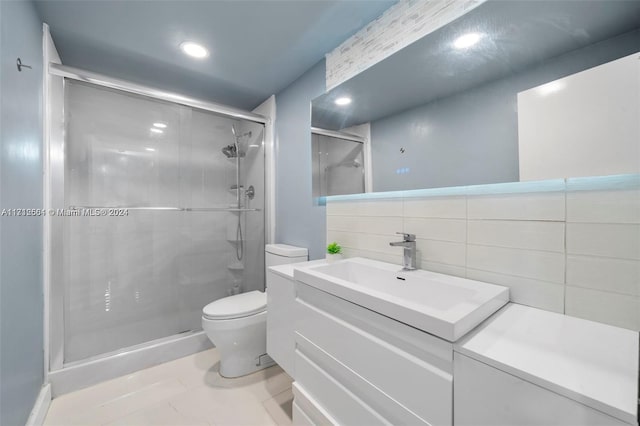 bathroom featuring a shower with door, vanity, tile walls, and toilet