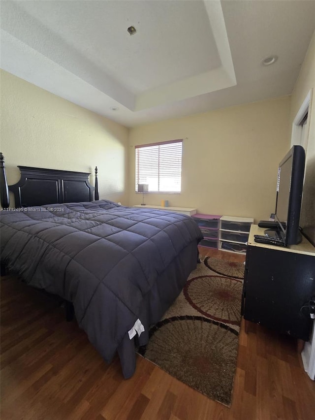 bedroom featuring dark hardwood / wood-style floors and a raised ceiling