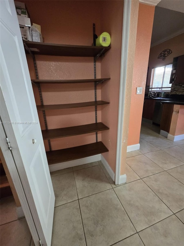 stairway with crown molding and tile patterned flooring