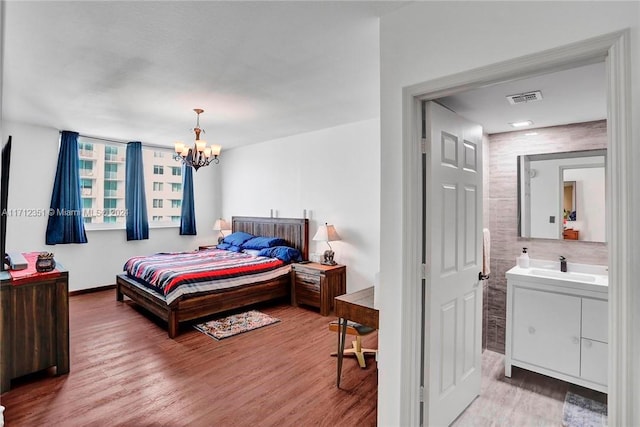 bedroom featuring hardwood / wood-style floors, a notable chandelier, sink, and tile walls