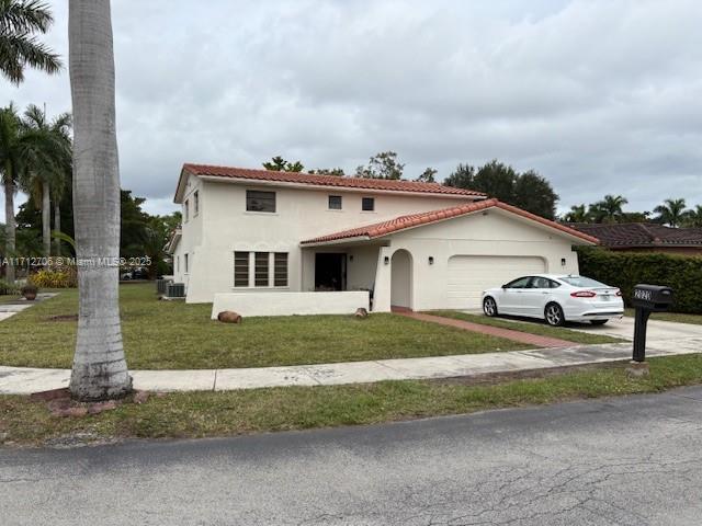 mediterranean / spanish-style house featuring a garage and a front lawn