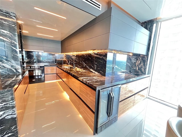 kitchen with backsplash, sink, dark stone countertops, black / electric stove, and beverage cooler