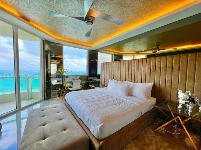 bedroom featuring ceiling fan, a water view, and multiple windows