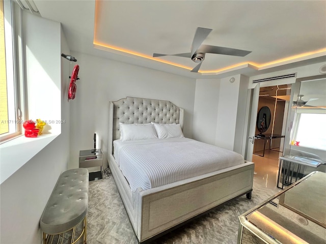 bedroom featuring ceiling fan, a tray ceiling, and multiple windows