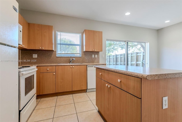 kitchen featuring tasteful backsplash, light tile patterned floors, a wealth of natural light, white appliances, and a sink