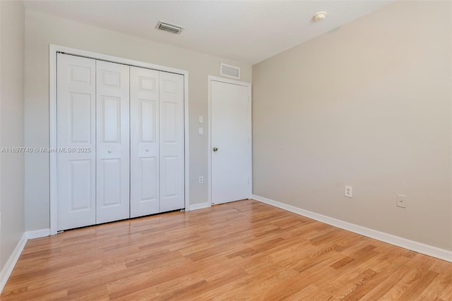 unfurnished bedroom featuring light wood-style flooring, baseboards, visible vents, and a closet