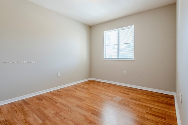 spare room with baseboards and light wood-style floors