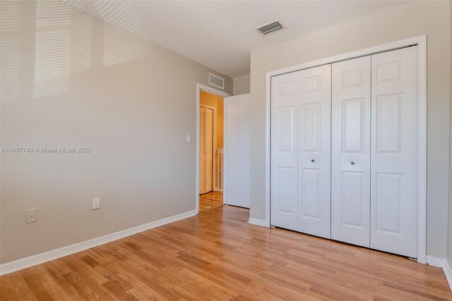 unfurnished bedroom featuring visible vents, light wood-style flooring, and baseboards