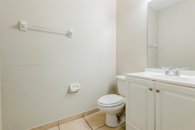 half bathroom with tile patterned floors, toilet, vanity, and baseboards