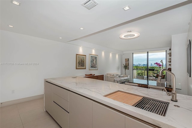 kitchen featuring light stone countertops, light tile patterned floors, white cabinets, and sink