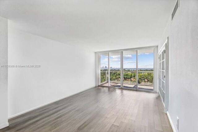 unfurnished room featuring dark hardwood / wood-style floors and a wall of windows