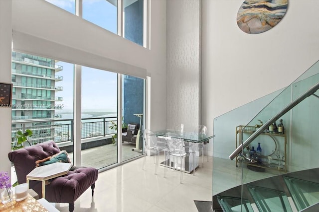 interior space with tile patterned flooring, a water view, and a high ceiling