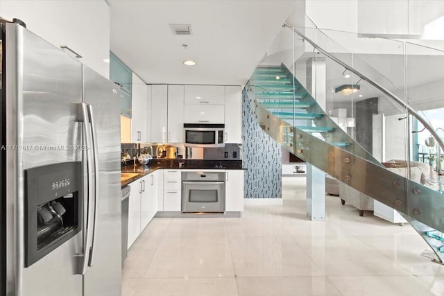 kitchen featuring white cabinetry, appliances with stainless steel finishes, decorative backsplash, and light tile patterned floors