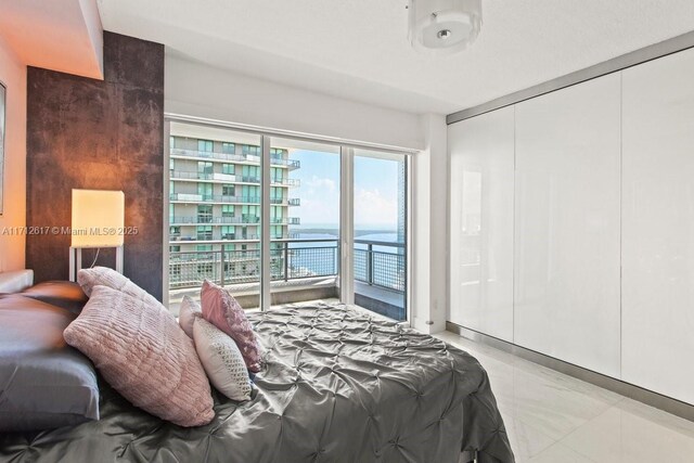 bedroom with access to outside, multiple windows, and a water view