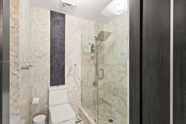 bathroom featuring toilet, a shower with door, and tile walls