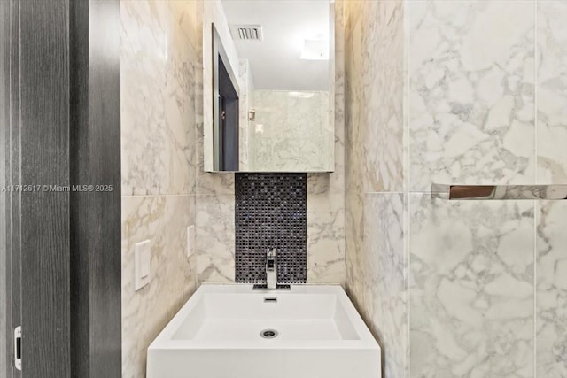 bathroom featuring sink and tile walls