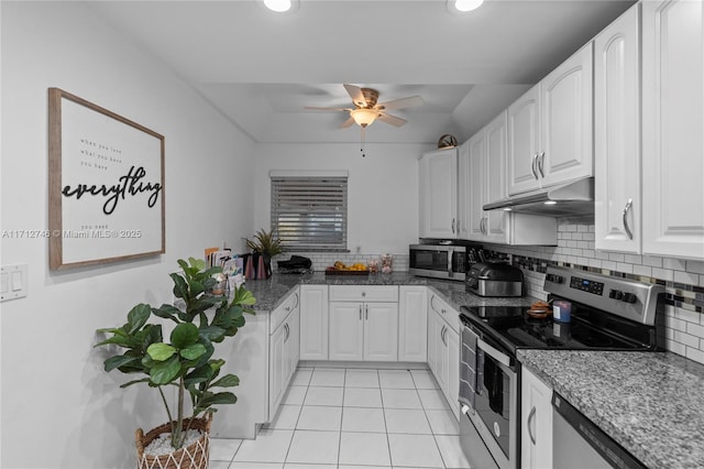 kitchen with appliances with stainless steel finishes, light tile patterned floors, tasteful backsplash, and white cabinetry