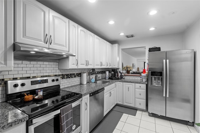 kitchen featuring stainless steel appliances, dark stone counters, white cabinets, decorative backsplash, and sink