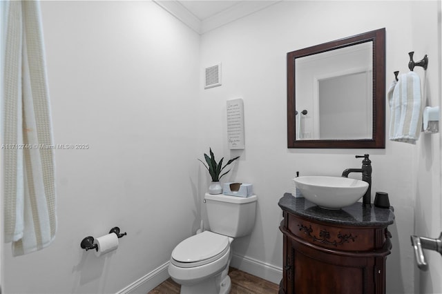 bathroom with hardwood / wood-style flooring, toilet, vanity, and crown molding