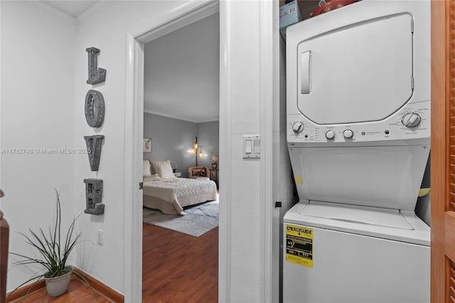 washroom featuring hardwood / wood-style flooring and stacked washer and dryer