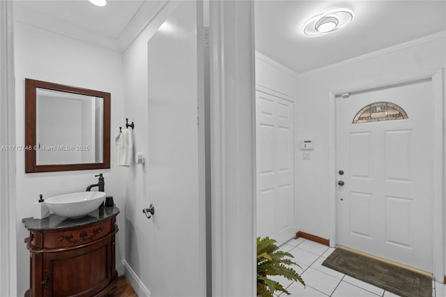 foyer with light tile patterned floors, sink, and ornamental molding