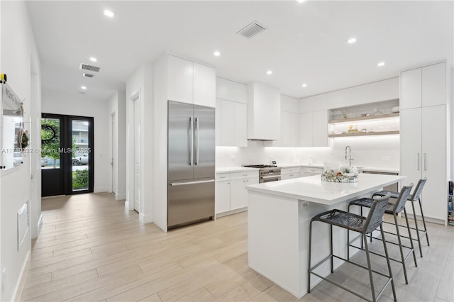 kitchen featuring premium appliances, visible vents, a breakfast bar area, and open shelves