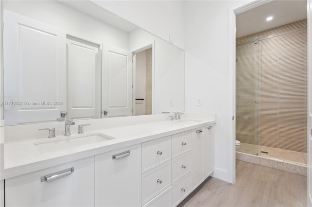 bathroom featuring double vanity, a stall shower, a sink, and toilet