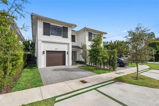 view of front of home with decorative driveway, an attached garage, and fence