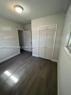 unfurnished bedroom featuring dark hardwood / wood-style flooring and a closet