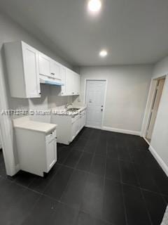 kitchen featuring dark tile patterned flooring and white cabinetry