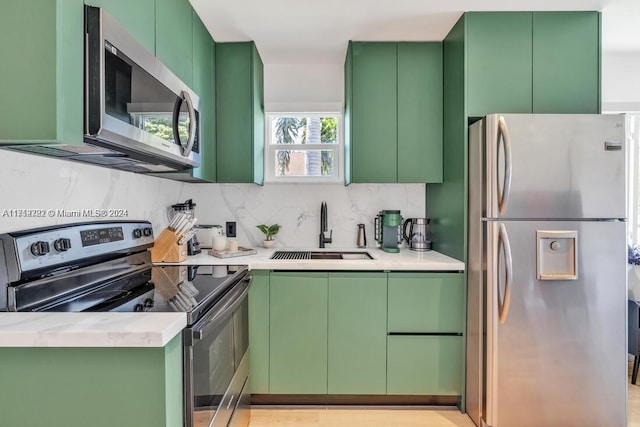 kitchen with stainless steel appliances, green cabinetry, and sink