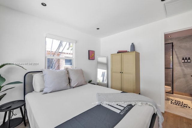 bedroom featuring connected bathroom and light hardwood / wood-style floors