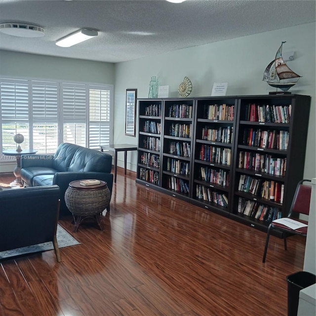 sitting room with a textured ceiling, wood finished floors, and bookshelves