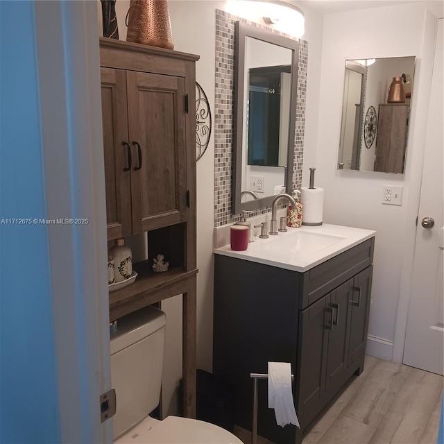 bathroom featuring toilet, vanity, and wood finished floors