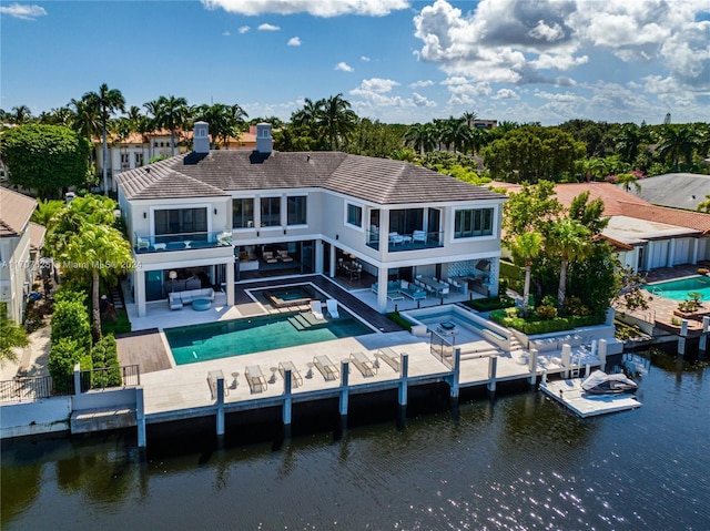 back of house featuring a pool with hot tub, a patio area, outdoor lounge area, and a balcony