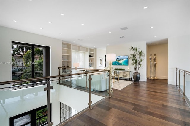 corridor featuring built in shelves and hardwood / wood-style floors