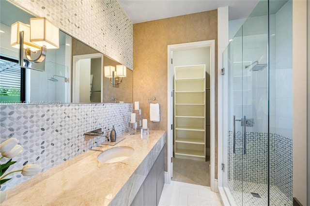 bathroom with tile patterned flooring, vanity, decorative backsplash, and a shower with door