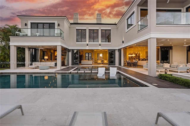 back house at dusk featuring outdoor lounge area and a patio