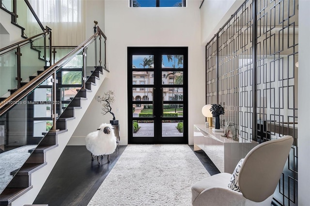 entrance foyer featuring a towering ceiling, wood-type flooring, and french doors