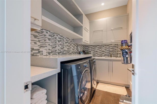 laundry area featuring washing machine and dryer, cabinets, and wood-type flooring