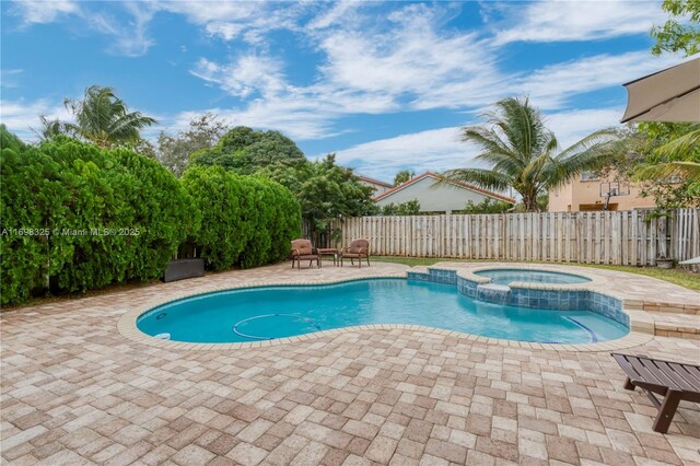 view of swimming pool featuring an in ground hot tub and a patio