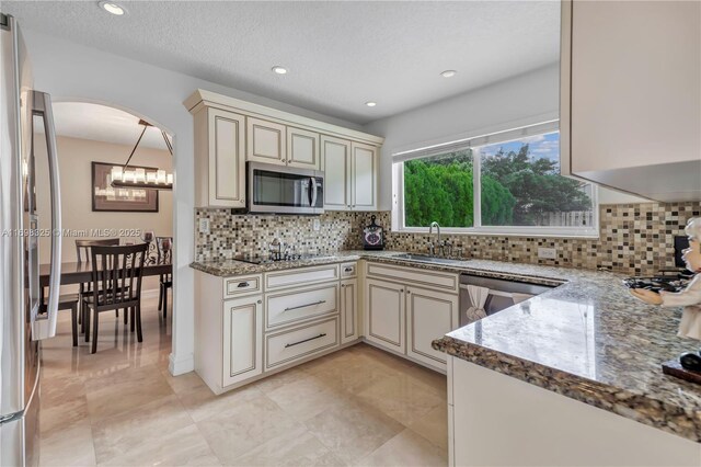 kitchen with decorative backsplash, sink, cream cabinetry, and appliances with stainless steel finishes