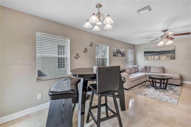 tiled dining room with ceiling fan with notable chandelier and a textured ceiling