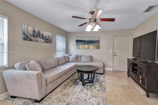 living room with ceiling fan, plenty of natural light, and a textured ceiling