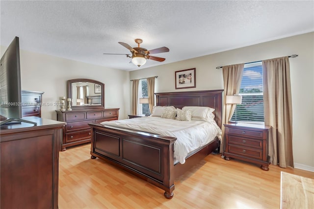 bedroom with ceiling fan, light wood-type flooring, and a textured ceiling