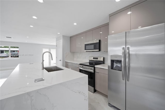 kitchen featuring light stone countertops, tasteful backsplash, stainless steel appliances, sink, and gray cabinets