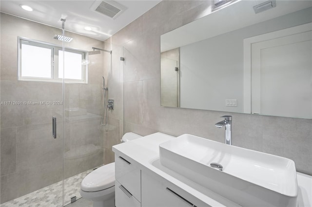 bathroom with vanity, toilet, an enclosed shower, and tile walls