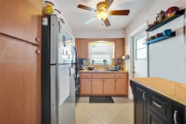 kitchen featuring ceiling fan, sink, stainless steel fridge, a textured ceiling, and light tile patterned floors