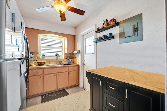 kitchen with backsplash, ceiling fan, sink, light tile patterned floors, and electric panel