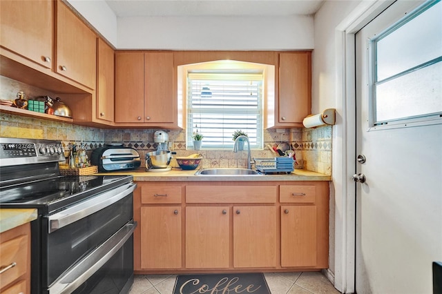 kitchen with light tile patterned floors, electric range, backsplash, and sink